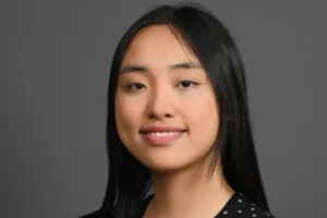 Corporate headshot of a woman with dark hair in a black patterned blouse