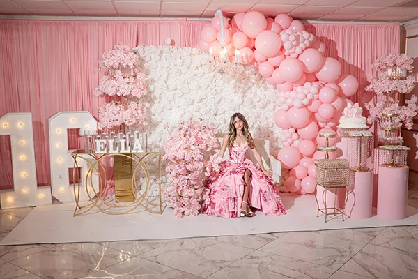 Birthday girl seated at the center of a pink balloon and floral backdrop at The Gran Centurions.