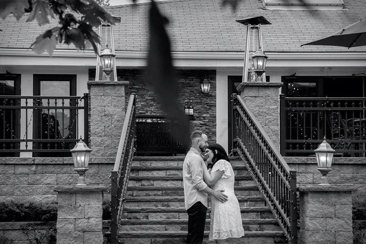 Black-and-white engagement portrait on the lodge staircase at Forest Lodge
