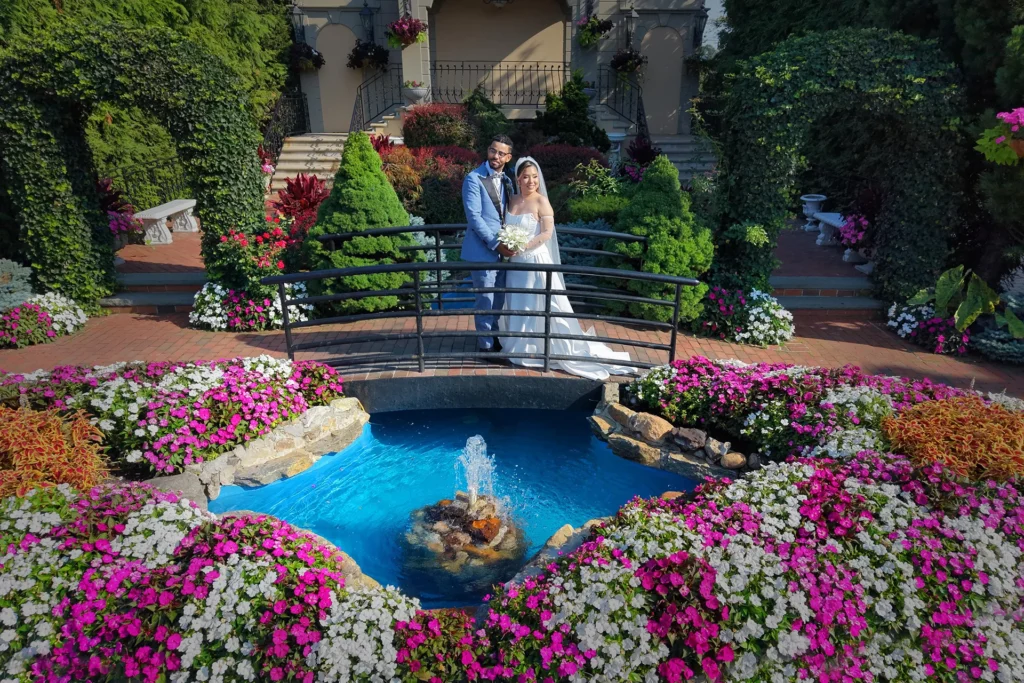 Bride and groom on the arched garden bridge above the fountain at Jericho Terrace in Mineola