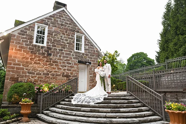 Bride and groom on the historic stone farmhouse steps at The Grove in Cedar Grove, NJ