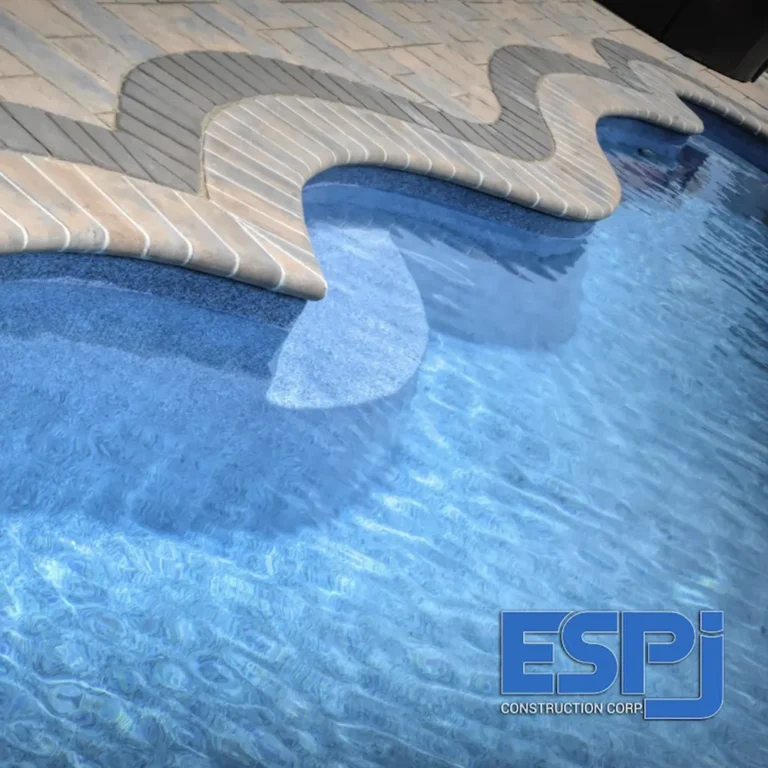 Detail photo of a custom inground pool with wave-shaped paver coping, shot for ESPJ Construction
