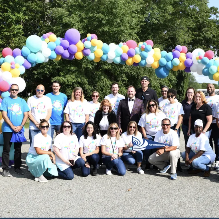 Corporate team group photo under a colorful balloon arch at a company celebration in New Jersey