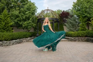 Birthday girl twirling her emerald gown on the stone patio by the gazebo